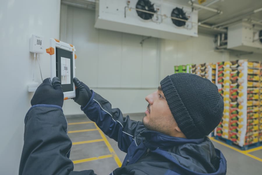 Empleado revisando un registrador de datos en un almacén