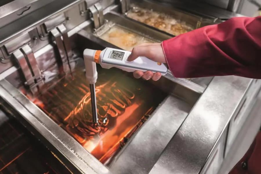 Mitarbeiter an der Fritteuse mit Messinstrumenten