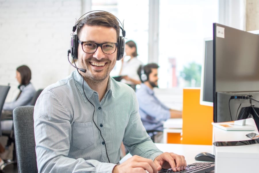 Smiling service employee at the computer with headset