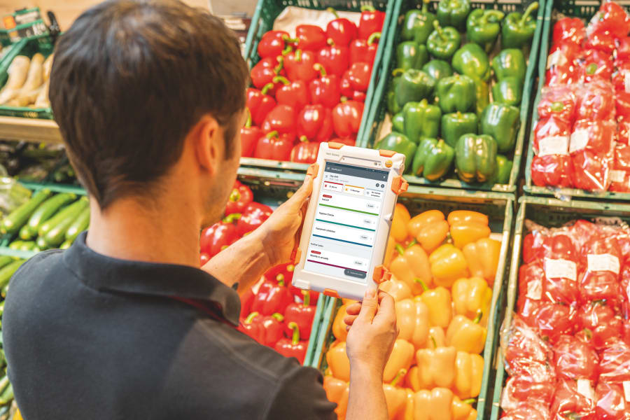 Mitarbeiterin mit Tablet in der Gemüseabteilung bei der Qualitätskontrolle
