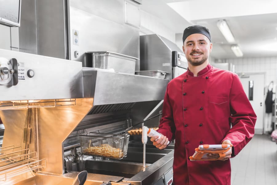 Employee at the deep fryer with measuring instruments